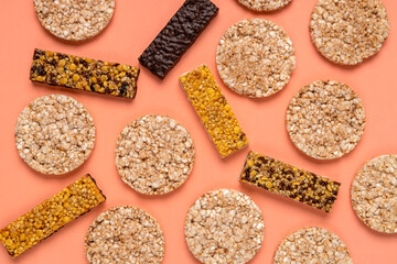 Top view of different kinds of fitness bars, crispbreads on the orange background. Texture of sport snacks