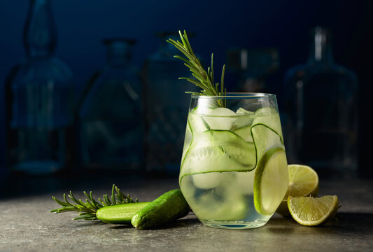 Cocktail gin tonic with ice, rosemary, lime, and cucumber.