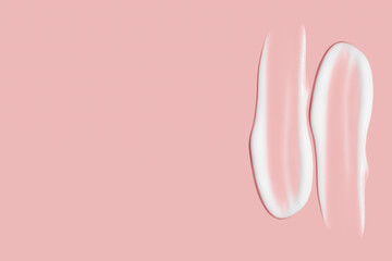 Lots of smears of cosmetic cream. Light, smooth surface. Texture of spreadable cream. Liquid creamy strokes. On a pink background. Cosmetic background, banner.