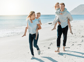 Fototapeta premium When we win, we win as a family. Shot of a couple carrying their daughters on their backs while at the beach.