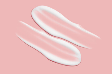Lots of smears of cosmetic cream. Light, smooth surface. Texture of spreadable cream. Liquid creamy strokes. On a pink background. Cosmetic background, banner.