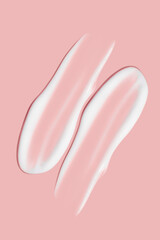 Lots of smears of cosmetic cream. Light, smooth surface. Texture of spreadable cream. Liquid creamy strokes. On a pink background. Cosmetic background, banner.