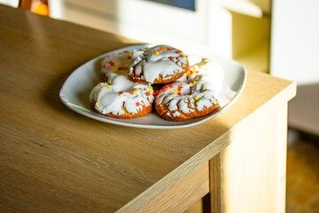 A plate of sweets with white icing, yellow red sprinkles Homemade Doughnuts, rosquillas, traditional anise donuts from Spain typically eaten in Easter, on rustic wooden table. Mediterranean sweet food