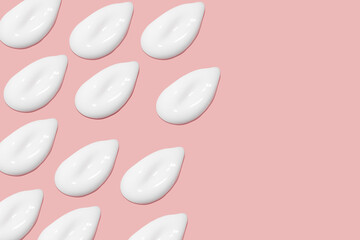 Lots of smears of cosmetic cream. Light, smooth surface. Texture of spreadable cream. Liquid creamy strokes. On a pink background. Cosmetic background, banner.