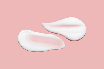 Lots of smears of cosmetic cream. Light, smooth surface. Texture of spreadable cream. Liquid creamy strokes. On a pink background. Cosmetic background, banner.