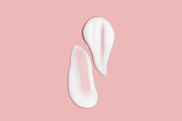 Lots of smears of cosmetic cream. Light, smooth surface. Texture of spreadable cream. Liquid creamy strokes. On a pink background. Cosmetic background, banner.