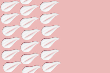 Lots of smears of cosmetic cream. Light, smooth surface. Texture of spreadable cream. Liquid creamy strokes. On a pink background. Cosmetic background, banner.