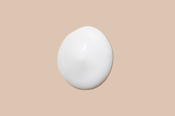 The flowing cream on a beige background. Smudged flowing smear of cosmetic cream.