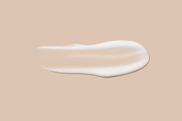 The flowing cream on a beige background. Smudged flowing smear of cosmetic cream.