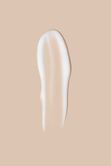 The flowing cream on a beige background. Smudged flowing smear of cosmetic cream.