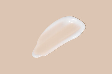 The flowing cream on a beige background. Smudged flowing smear of cosmetic cream.