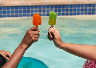Close up of friends holding ice lolly popsicles in the swimming pool, beat heat - Powered by Adobe