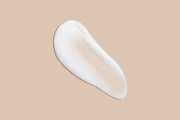 The flowing cream on a beige background. Smudged flowing smear of cosmetic cream.