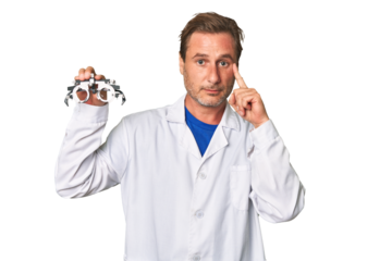 A middle-aged optometrist man pointing temple with finger, thinking, focused on a task.