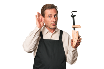 A middle-aged shoe maker trying to listening a gossip.