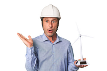 A middle-aged architect man holding a windmill model surprised and shocked.