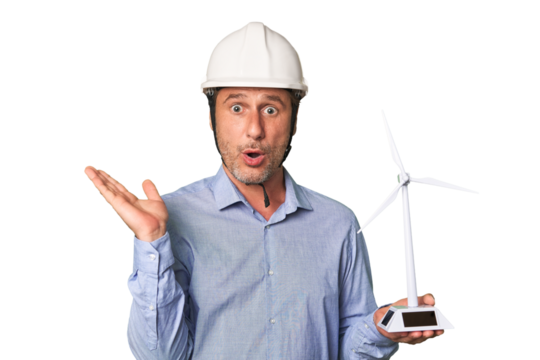 A middle-aged architect man holding a windmill model surprised and shocked.
