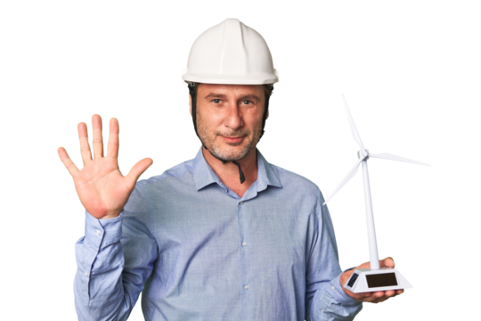 A middle-aged architect man holding a windmill model smiling cheerful showing number five with fingers.