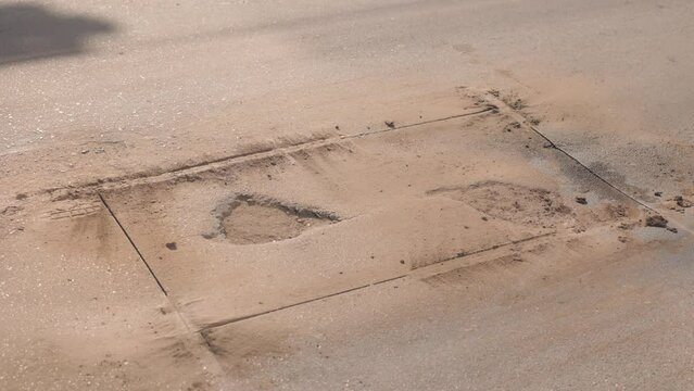Pothole repair on a road. An overall view of a road pothole after cutting out a rectangle with a circular saw, and before removing the asphalt to make way for new pavement.