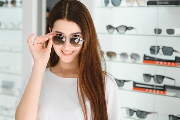 She made her choice. Beautiful young woman adjusting her new sunglasses and smiling while standing in optic store.