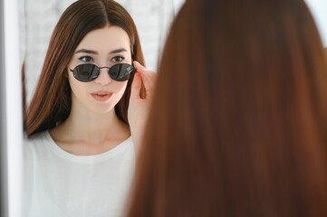 She made her choice. Beautiful young woman adjusting her new sunglasses and smiling while standing in optic store.