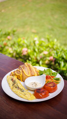 breakfast dish with savory croissant with Omelette, served with fresh healthy salad on a white plate and dipping sauce
