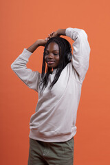 Cheerful black woman in headphones touching head on orange background