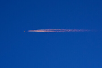 Flugzeug mit Kondensstreifen im Sonnenuntergang