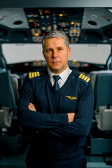 Portrait of serious airplane captain in uniform preparing for flight in aero simulator cockpit