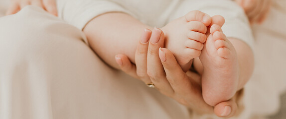 Banner. Loving mother holding in the hands feet of newborn baby. Baby feet in mother hands. Tiny Newborn Baby's feet on female hands closeup. Mom and her Child. Happy Family concept.