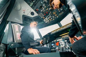 An experienced pilot instructs a young student before a training flight in the cockpit of an aero simulator