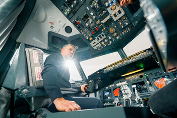 An experienced pilot instructs a young student before a training flight in the cockpit of an aero simulator