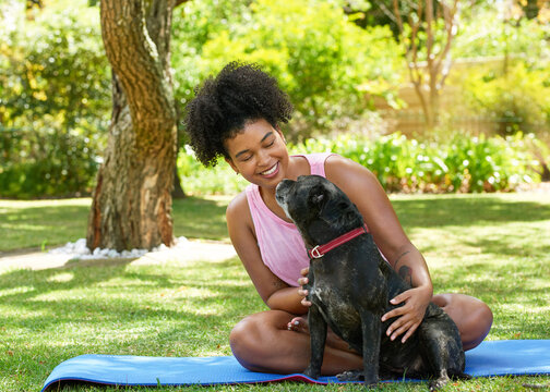A multi-ethnic woman and her happy dog, giving attention in the park pet owner