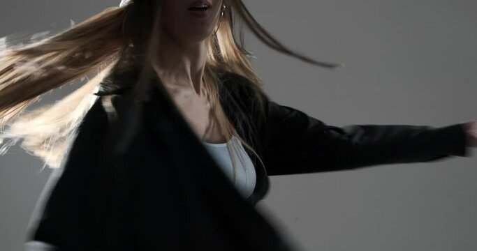 Active woman in sports bra and unbuttoned shirt dancing in hip hop style