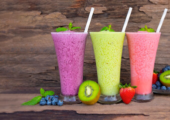 Kiwi strawberry and blueberry smoothies colorful fruit juice green purple and red milkshake blend beverage healthy high protein the taste yummy In glass drink episode morning on wood background.