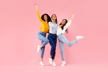 Female friendship concept. Joyful diverse ladies embracing and having fun together over pink background, full length