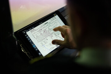 the pilot holds a tablet in his hands, looks at the flight route and chooses the landing place of...