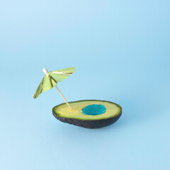 Swimming pool made of sun umbrella and raw avocado fruit. Creative minimal vacation and summer concept.