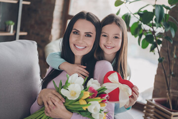 Portrait of loving family kid girl celebrate mother day hug embrace mommy give blossom bouquet present box in flat