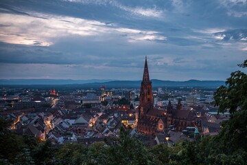 Blick auf die Stadt Freiburg (Deutschland) von oben bei Sonnenuntergang und aufziehendem Gewitter über den Vogesen