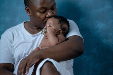 African father holds and comforting 3 months old baby girl in arms, baby was feeling sick and...