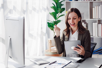 Overjoyed young businesswoman with digital tablet expressing excitement rejoicing in home office,...