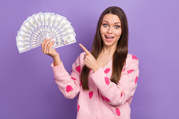 Photo of young amazed lottery player betting girl much dollars direct fingers income jackpot hooray success rich isolated on purple color background