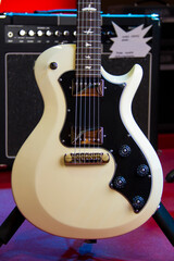 Plakat Close up of a solid white electric guitar with humbucker pickups, black pickguard and silver hardware.