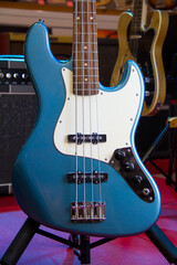 Close up of solid blue electric bass guitar with single coil pickups and silver hardware
