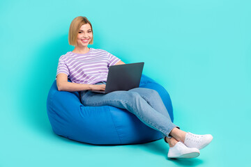 Full body photo cadre of young sitting beanbag girl programmer use netbook chatting with customers...