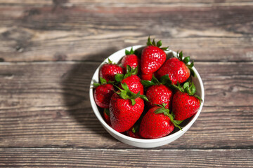 Fresh Bowl of strawberries on a wooden table.