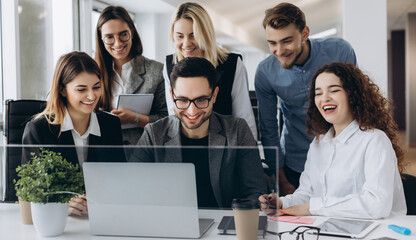 Startup business team on meeting in modern bright office interior smiling and working on laptop.