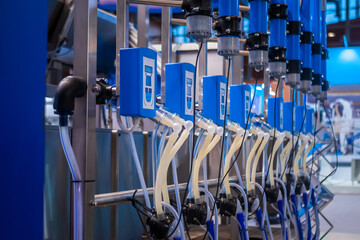 Automated goat milking suction machine with teat cups at cattle dairy farm, exhibition, trade show. Farming, automated technology equipment, agriculture industry, animal husbandry concept