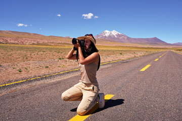 young woman photographer in the middle of a road squatting taking photos of nature in Los Flamencos...